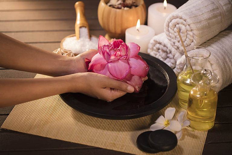 massage natural oils, rose patels in female hand and towels